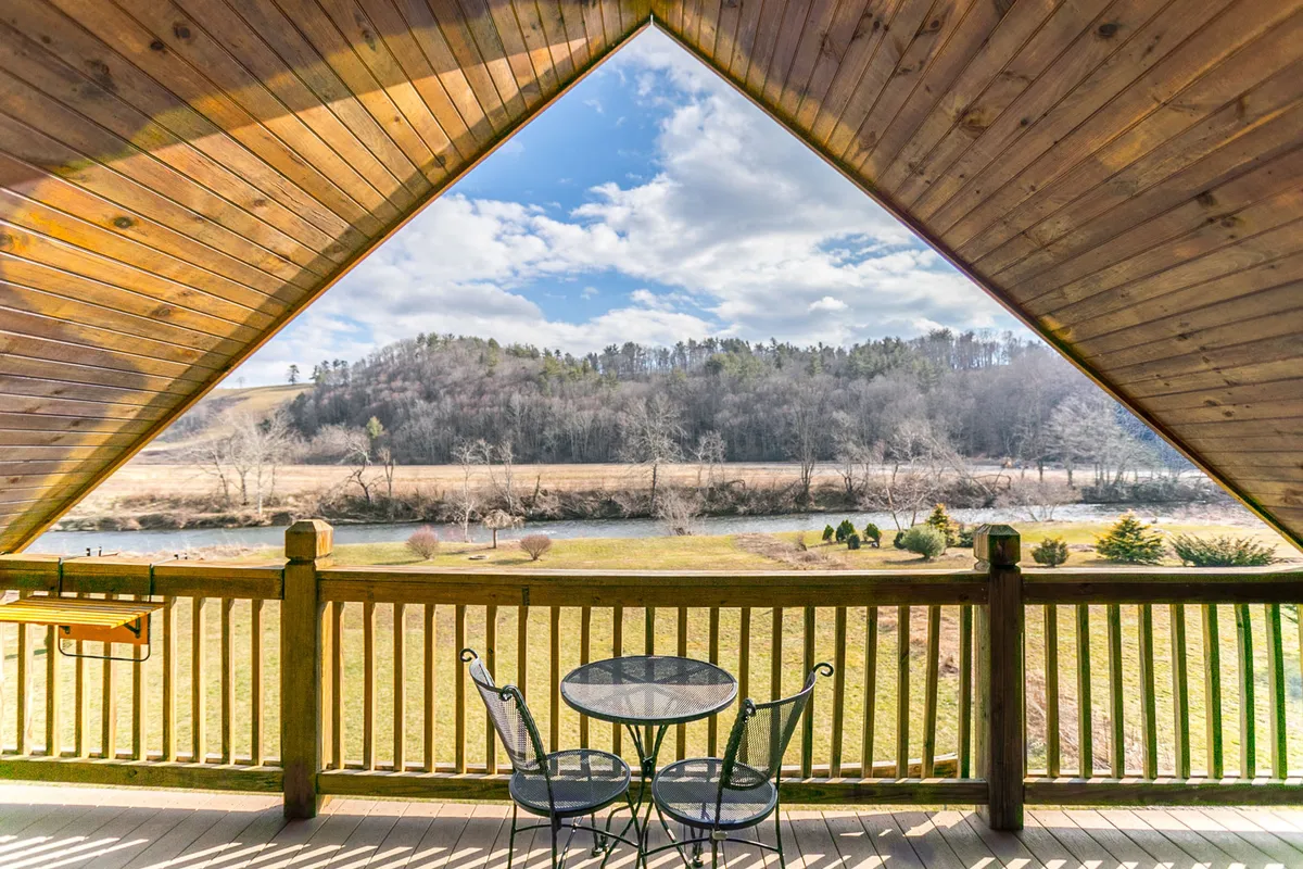 A tranquil covered porch with a table and chairs overlooking an expansive river and lush greenery—an inviting spot for morning coffee, meditation, or birdwatching.