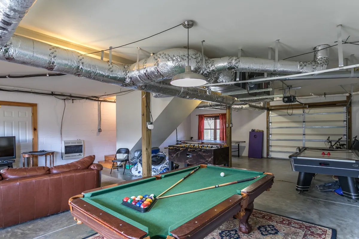 A lively game room featuring a pool table, air hockey table, sofa for seating, and a bar area. The space is well-lit and designed for both active play and relaxation, inviting families and groups to enjoy friendly competition and socializing.