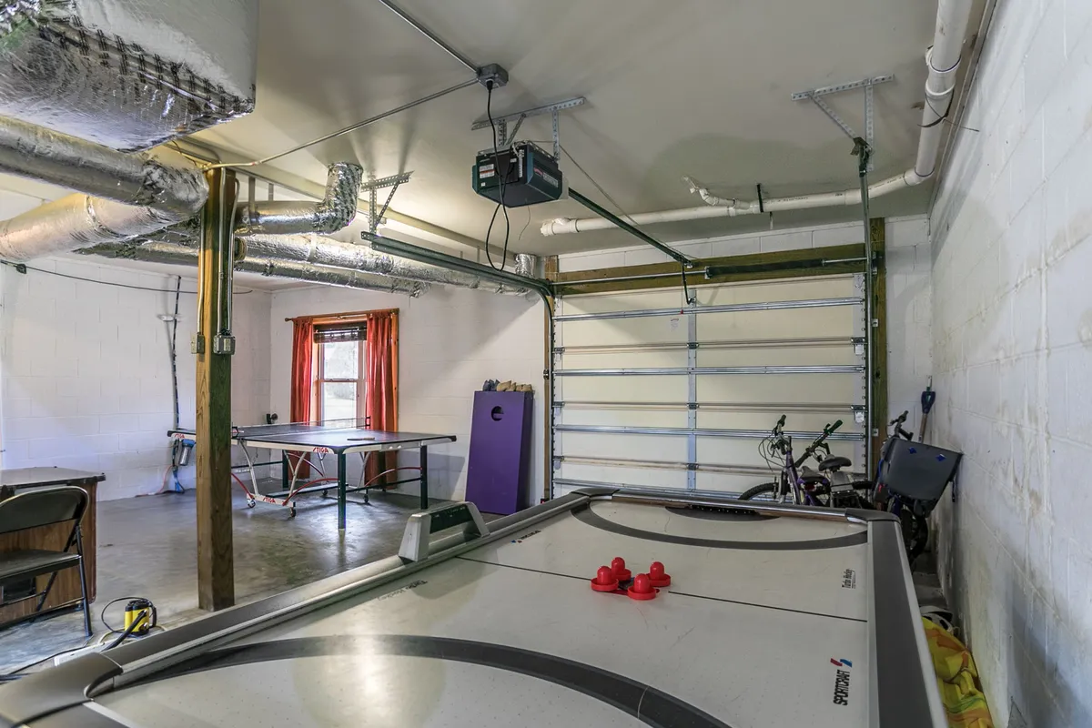 A relaxed and playful interior with an air hockey table, ping pong table, bicycle storage, and a window letting in natural light. The room is geared toward group games and social gatherings, with a casual, youthful vibe.