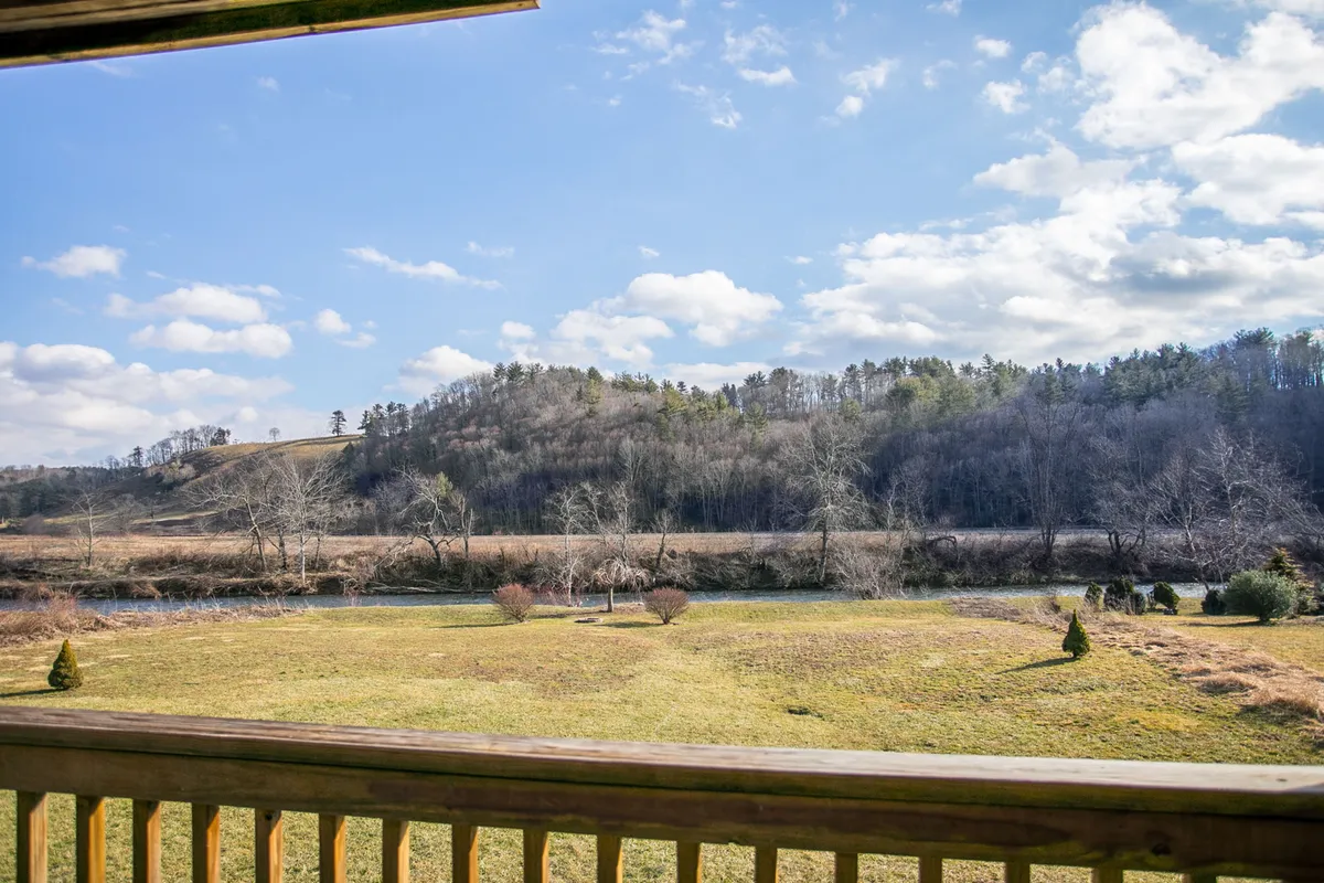 A sweeping view of rolling hills, the winding river, distant trees, and an open field. The landscape is tranquil and inviting, suggesting ample opportunities for birdwatching, hiking, picnicking, and enjoying the beauty of the natural surroundings.